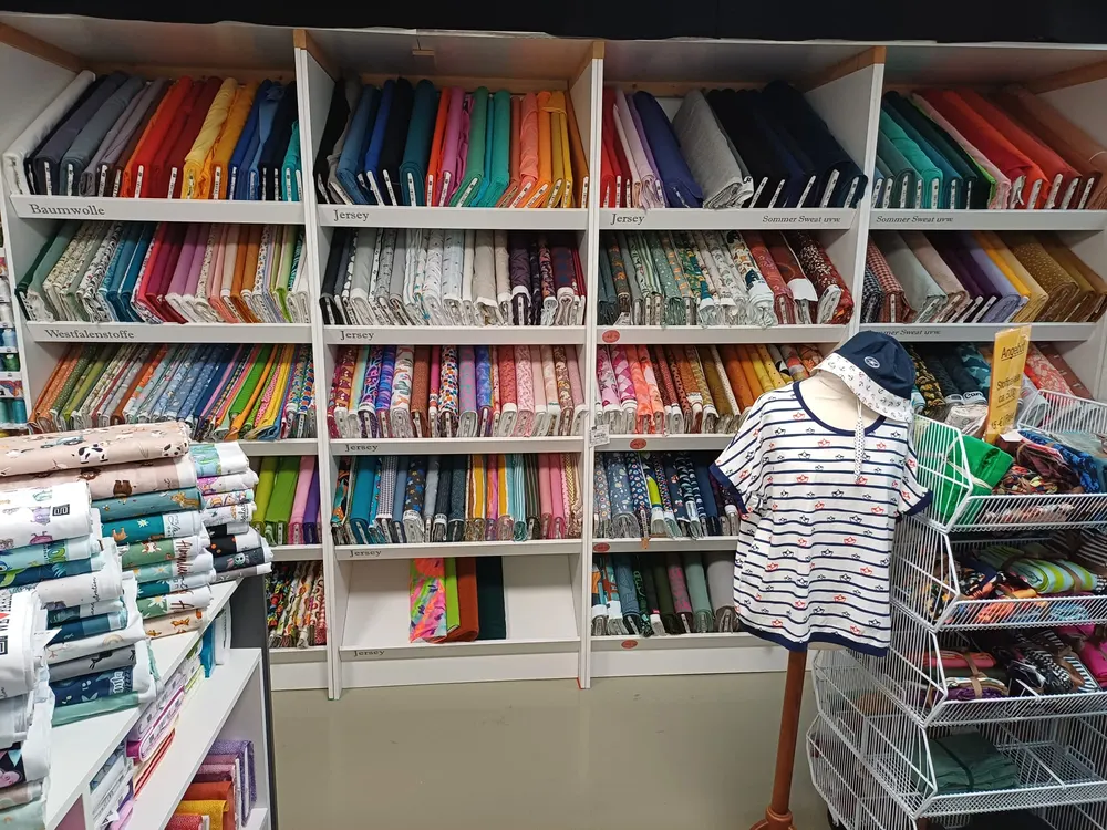 Stoffregale mit Baumwoll- und Jerseystoffen in verschiedenen Farben und Mustern im Laden